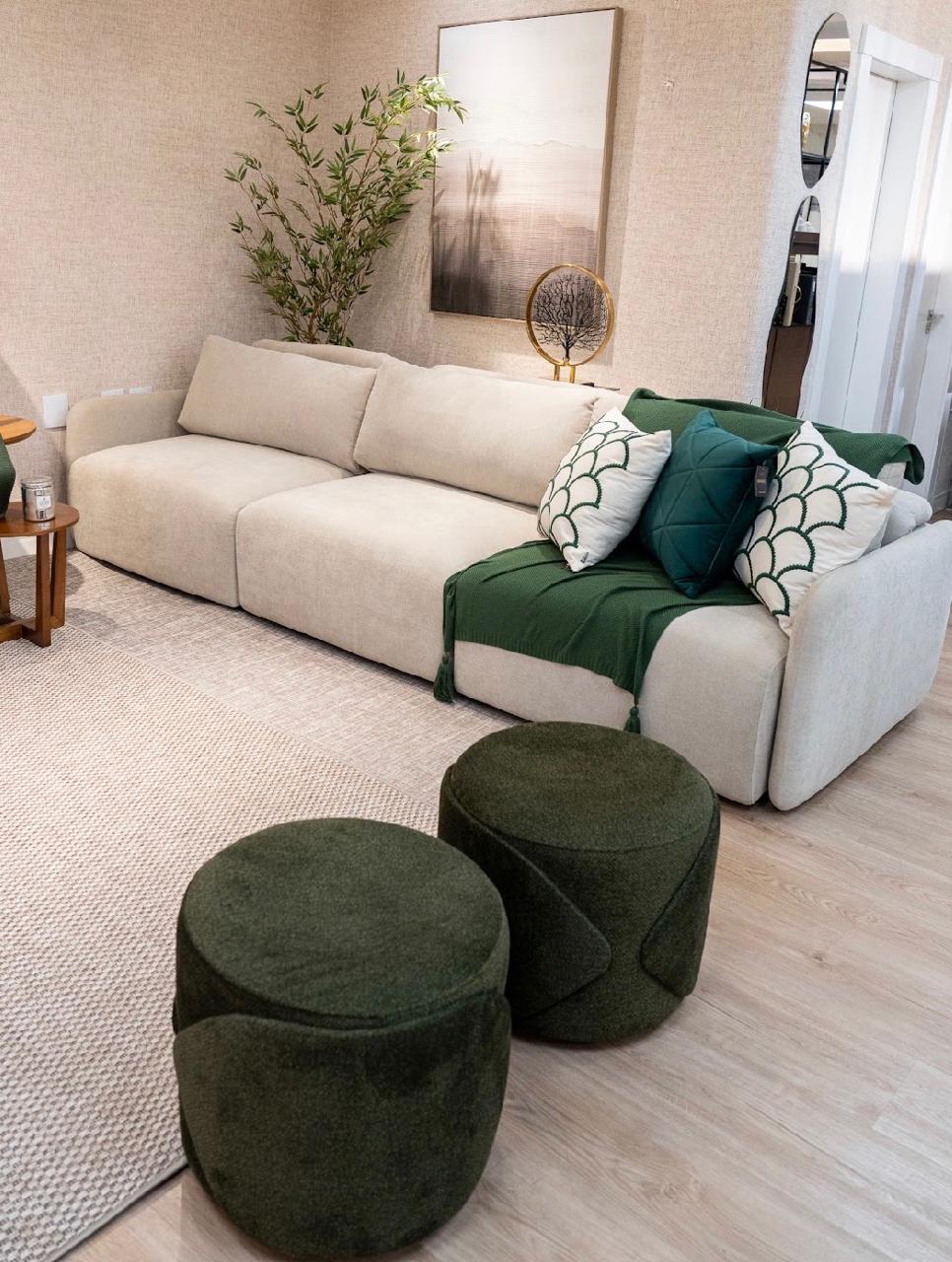 Sofá modular bege com almofadas verdes e dois puffs redondos verde musgo