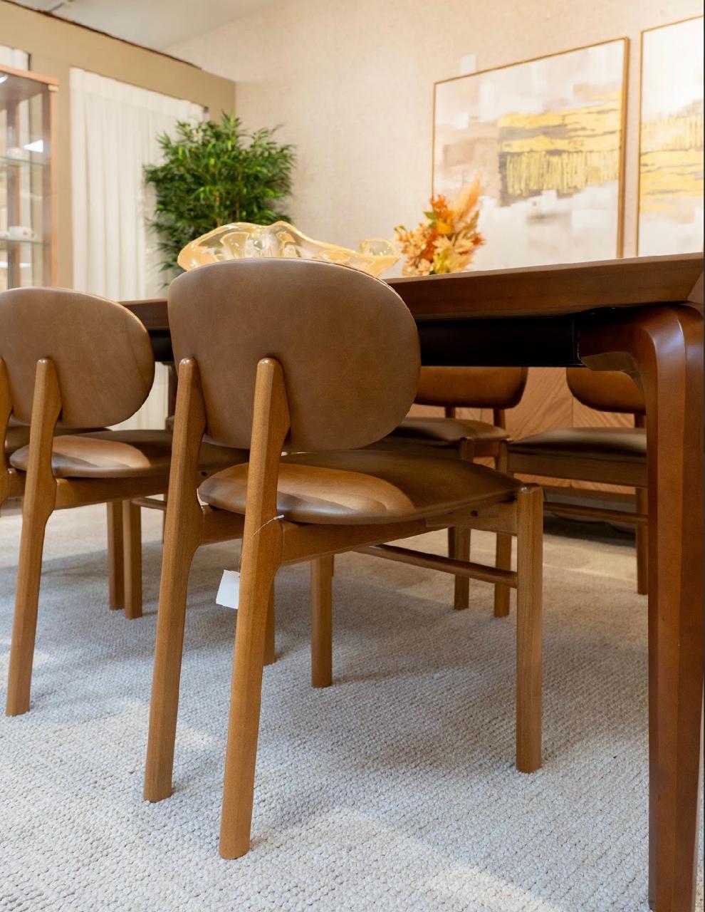 Mesa de jantar de madeira natural com cadeiras de couro claro sobre tapete texturizado