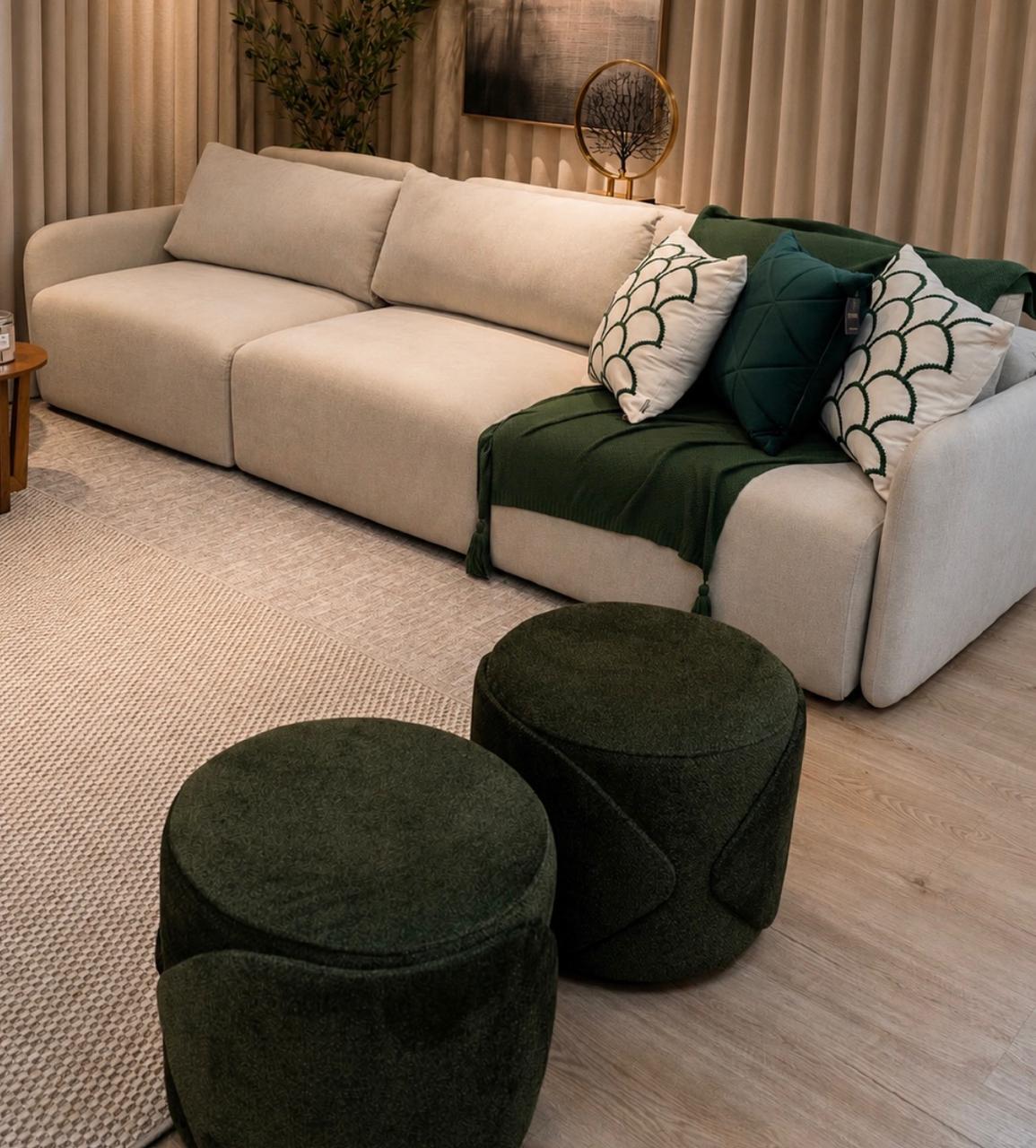 Living com sofá modular bege, manta verde e dois puffs redondos verde musgo sobre tapete claro