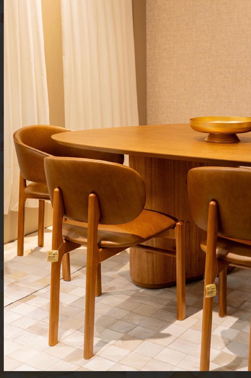 Mesa de jantar oval de madeira com cadeiras estofadas em couro caramelo e centro dourado